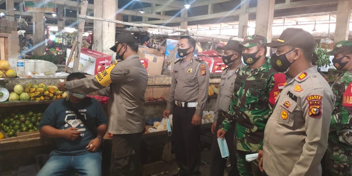 Kapolsek Siak Hulu Gandeng Anggota Babinsa Bagikan Masker di Pasar Syariah Ulul Albab