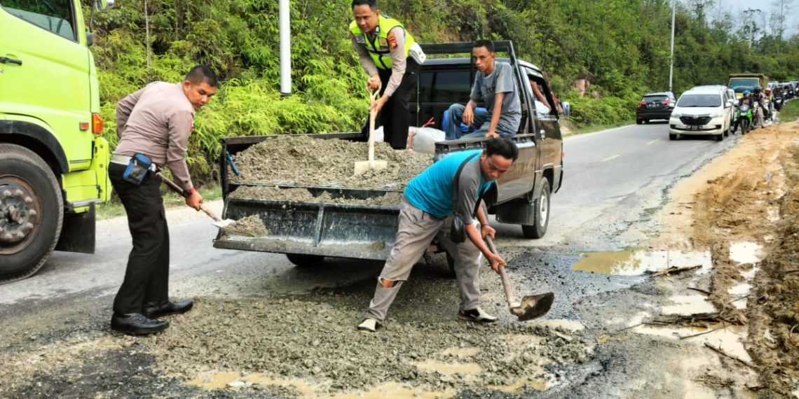 Peduli Keselamatan Pengendara, BKO Lantas Polsek XIII Koto Kampar Timbun Secara Manual Jalan Lintas Nasional Berlubang